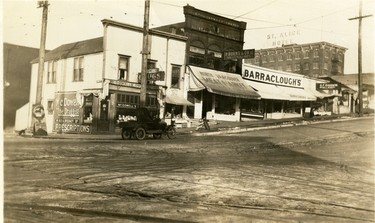 1918: A Model T. Ford pick up truck is parked on the 100 block Lonsdale Avenue, which included McDowell's Drug Store, Chas. Cartlidge Produce, North Vancouver Meat Market, Barraclough's Grocery and G.F. Goodwin Greengrocer. The St. Alice Hotel can be seen in the distance.