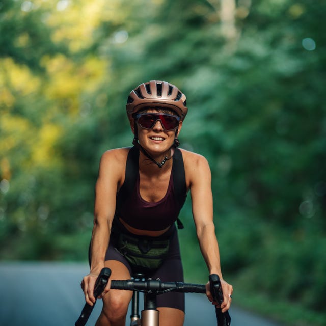 Female cyclist enjoying a ride on a forest road Female cyclist enjoying a ride on a forest road