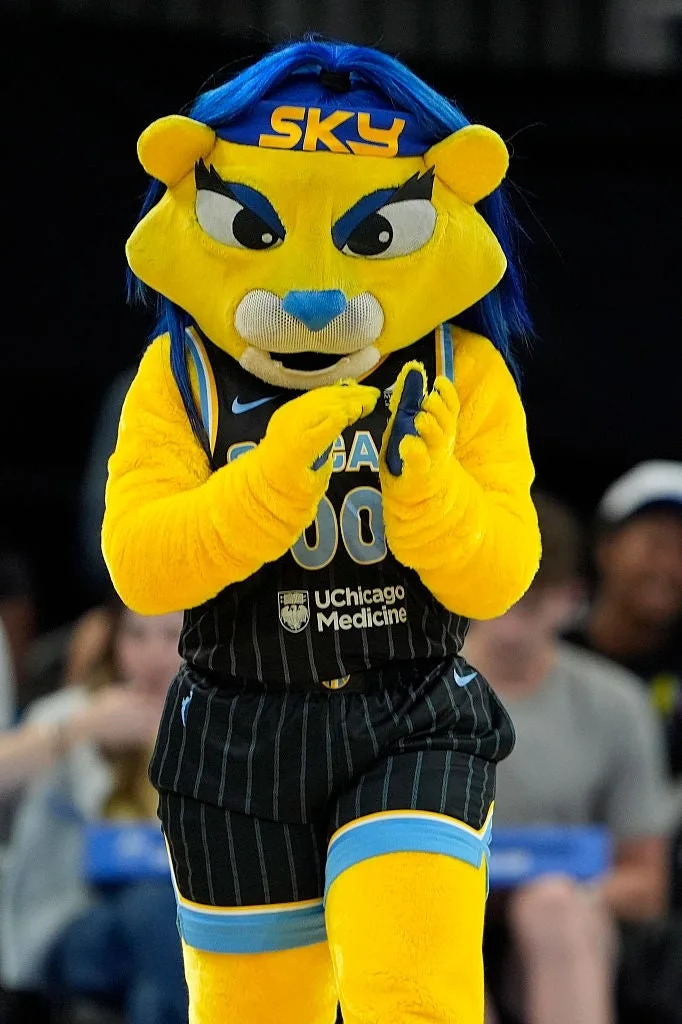 Mascot in a basketball jersey clapping at a sporting event