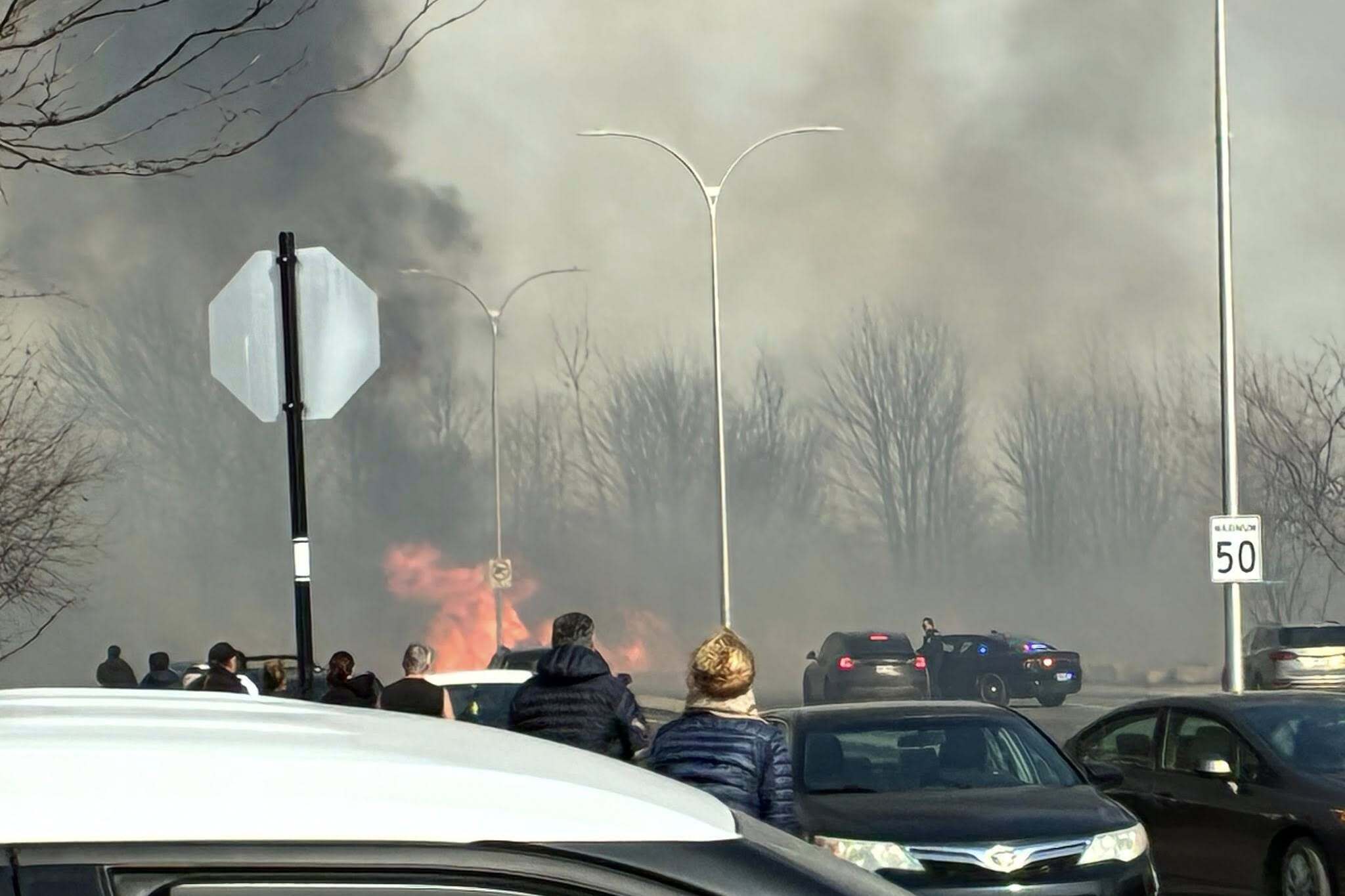 Crowd gathers to look at fire, sky filled with smoke 