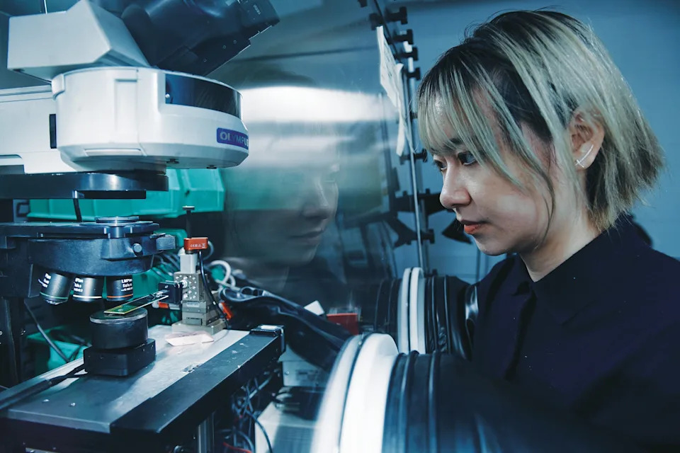 A woman with short hair working with a large microscope.