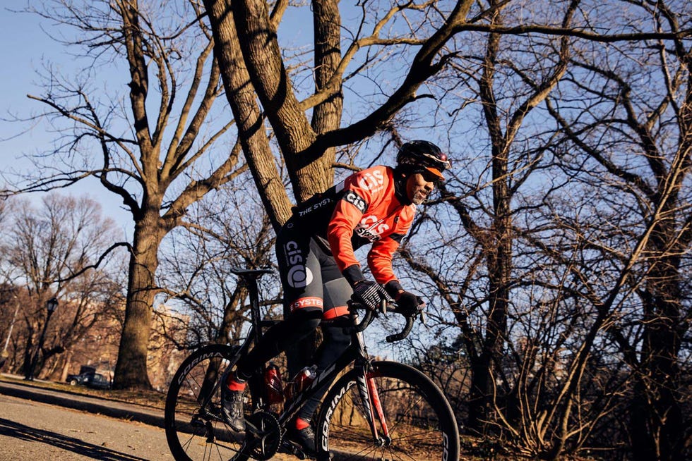 Cyclist riding on a path surrounded by trees in a park. Cyclist riding on a path surrounded by trees in a park.