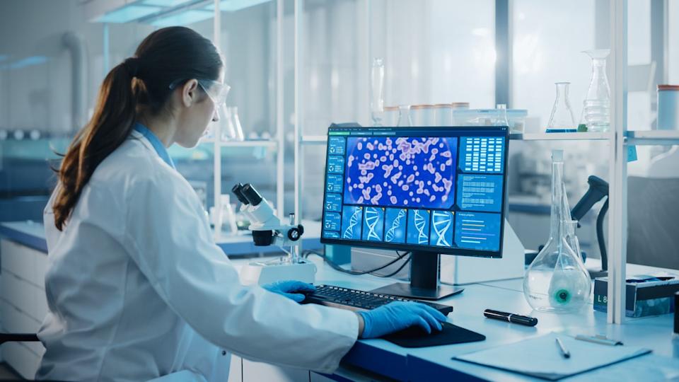 A pharmaceutical lab technician is working at a computer.
