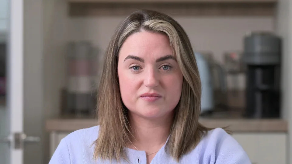 Alyssa McCrea is sitting in a kitchen. She has shoulder length fair hair. She's wearing a lilac cardigan and a silver necklace.  