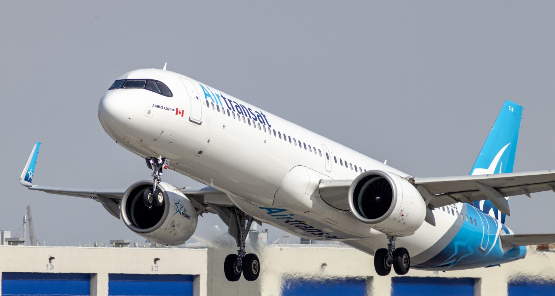 And Air Transat jet plane takes off with buildings in the background.