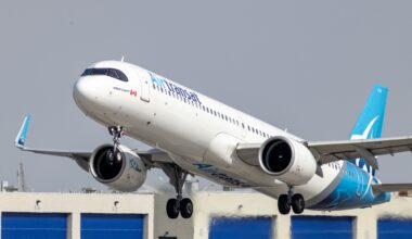 And Air Transat jet plane takes off with buildings in the background.