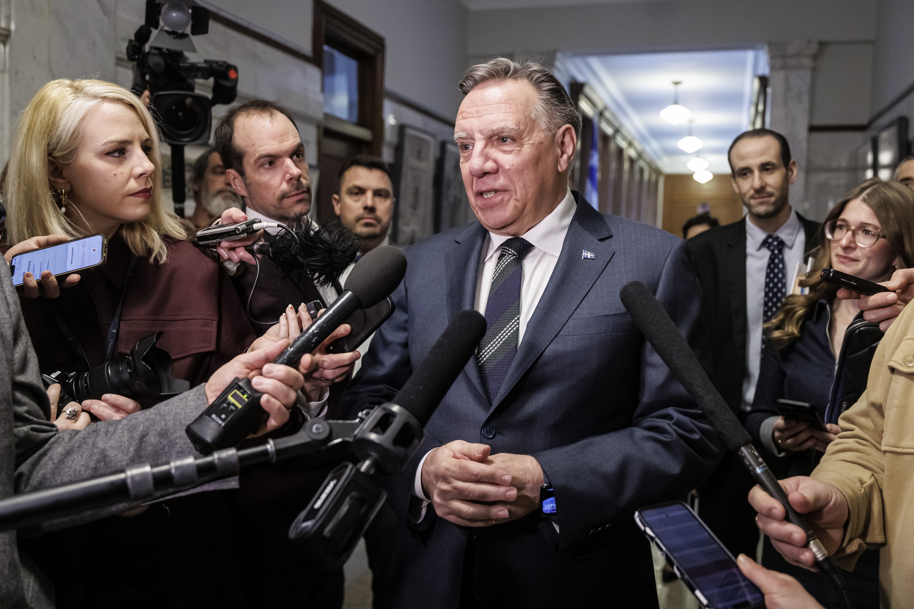 François Legault speaks to journalists scrumming around him in a National Assembly corridor