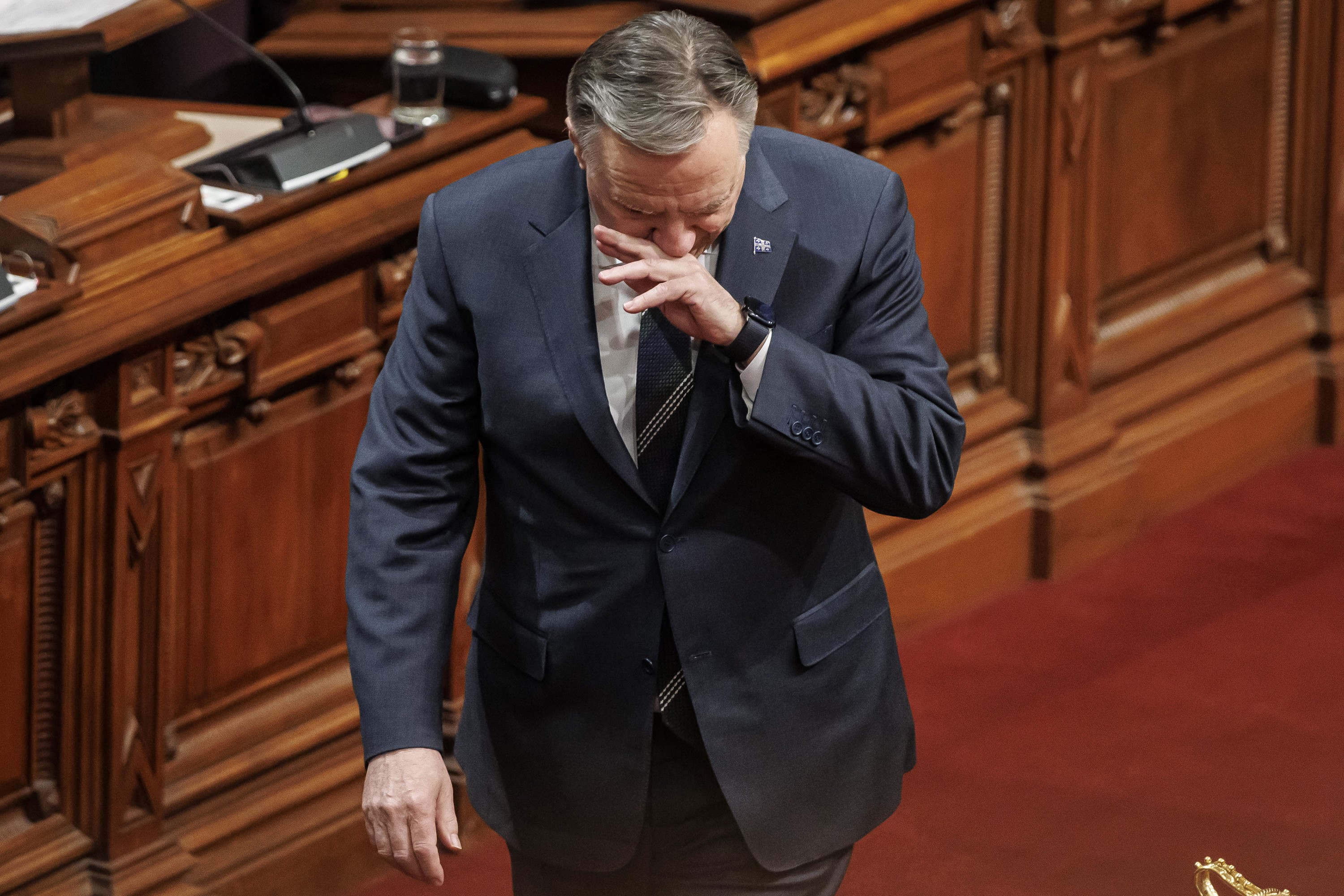 François Legault wipes his face with his hand as he walks in the National Assembly's red room