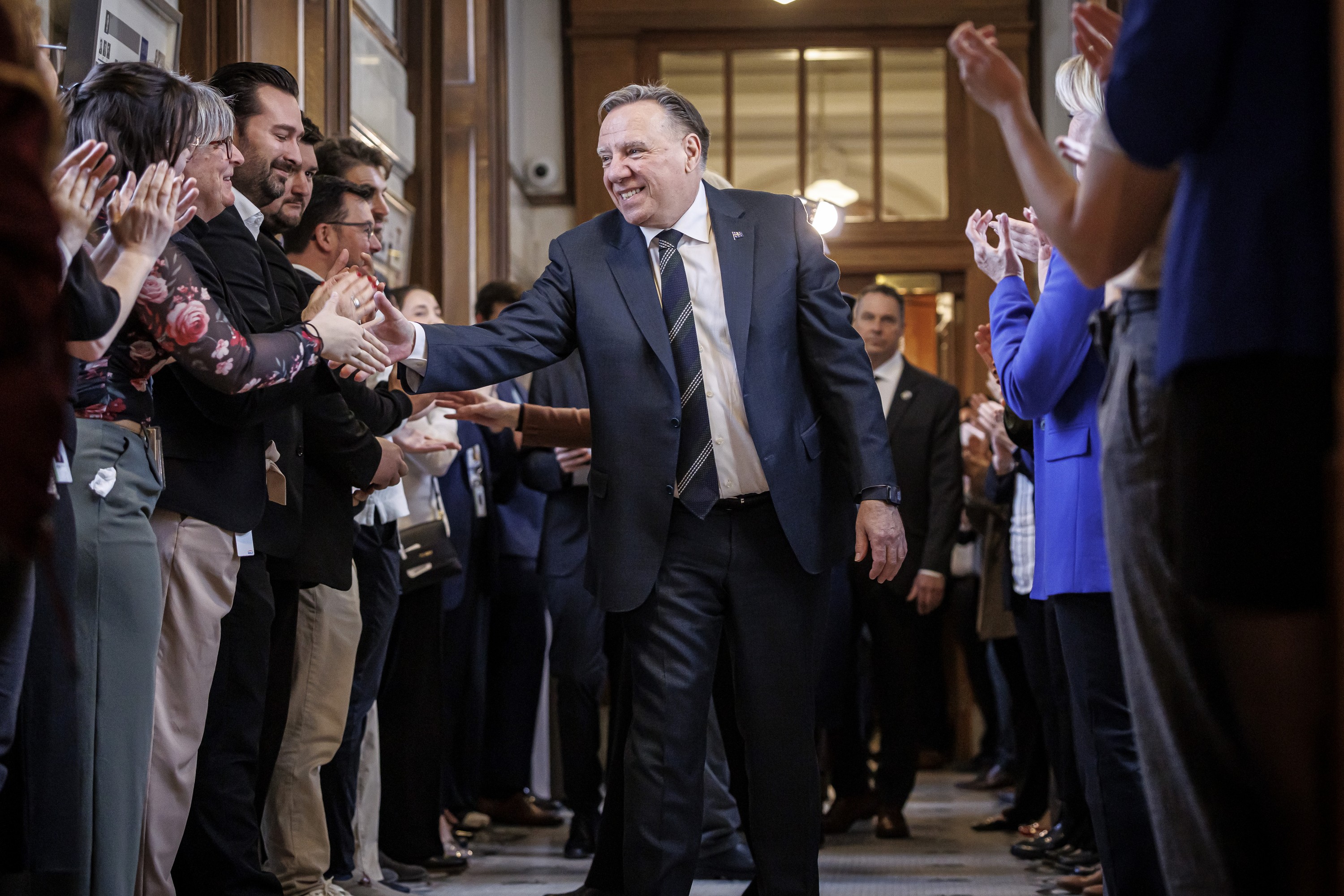 François Legault shakes the hands of people lined up on both sides of a hallway
