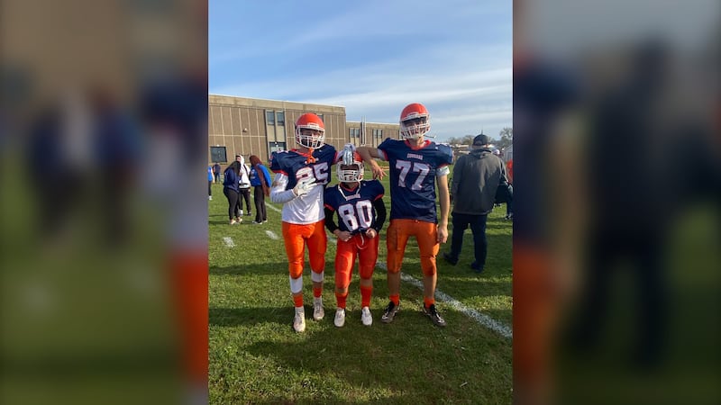 Julia Cameron is pictured on the field in her football gear between taller teammates.