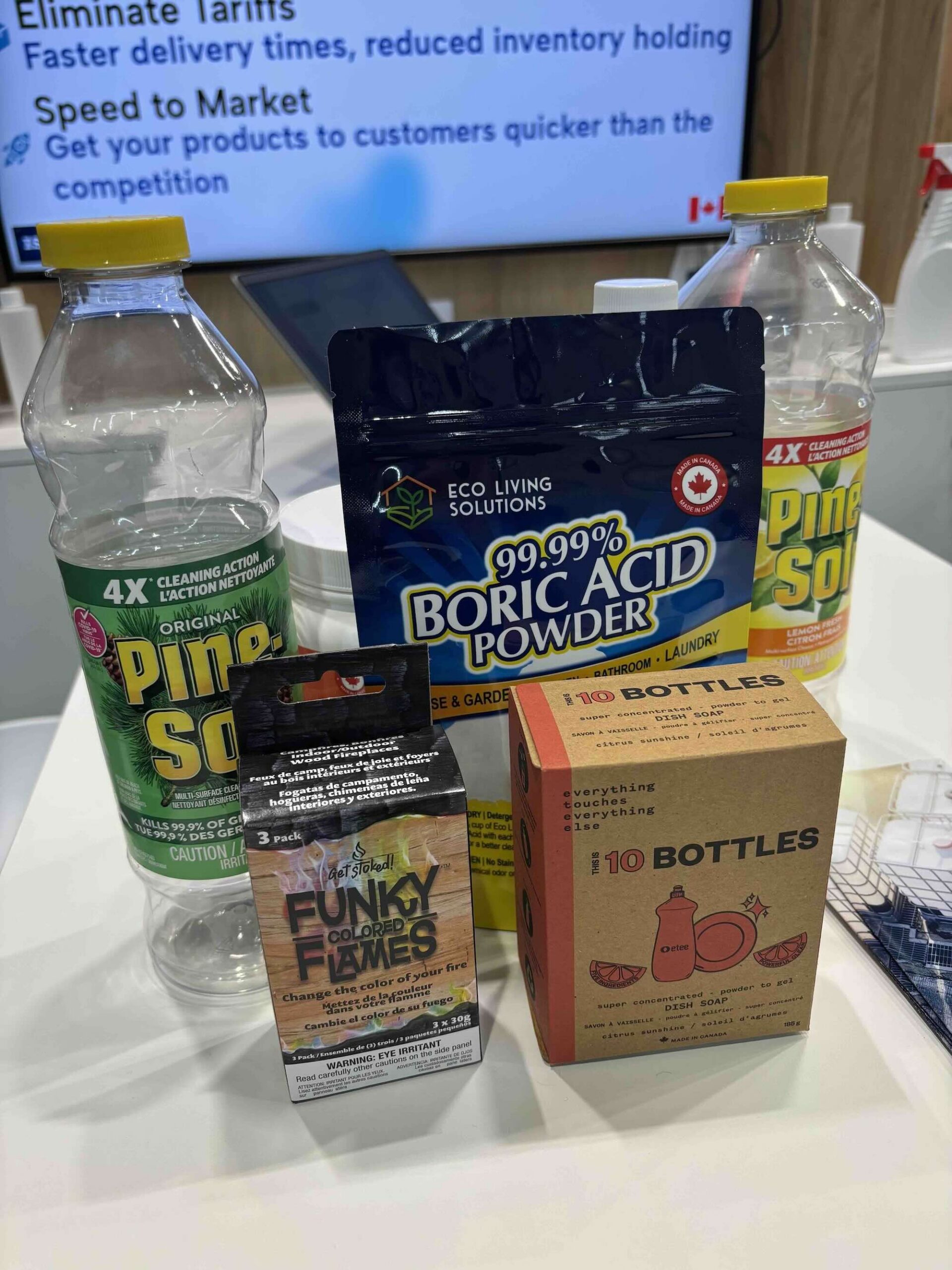 A close-up of various containers of chemical cleaning products, including Pine-Sol and boric acid powder, on a table.