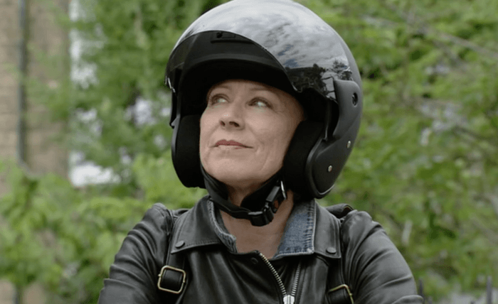 EastEnders Carol exit Lindsey Coulson as Carol Jackson smiling while sat on a motorcycle and wearing a helmet in EastEnders.