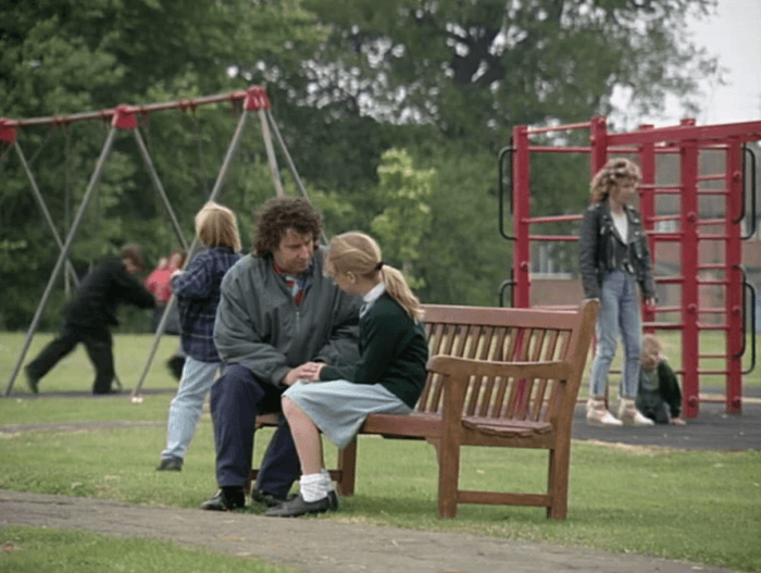 EastEnders Nigel tells Clare A long shot of Paul Bradley as Nigel Bates speaking with Gemma Bissix as Clare Bates on a park bench in a scene from EastEnders in the 1990s.