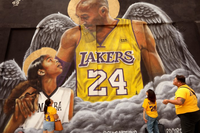 LOS ANGELES, CA - AUGUST 23, 2020 - - Elizabeth Muñoz, from left, her sister Maria Muñoz and their nephew David Muñoz, from Huntington Park, pay their respects at a Kobe Bryant mural on what would have been Bryants 42nd birthday along Grand Avenue in downtown Los Angeles on August 23, 2020. The Muñoz were visiting as many murals of the late Lakers star and leaving flowers to wish him a Happy Birthday. Thanks for all the memories. Well never forget you, Elizabeth said. The mural was created by Sloe Motions. (Genaro Molina / Los Angeles Times via Getty Images)