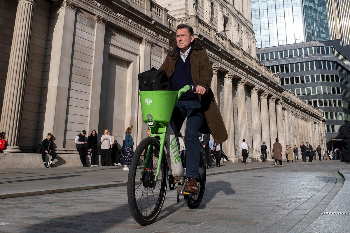 Man cycling Lime Bike in City of London.