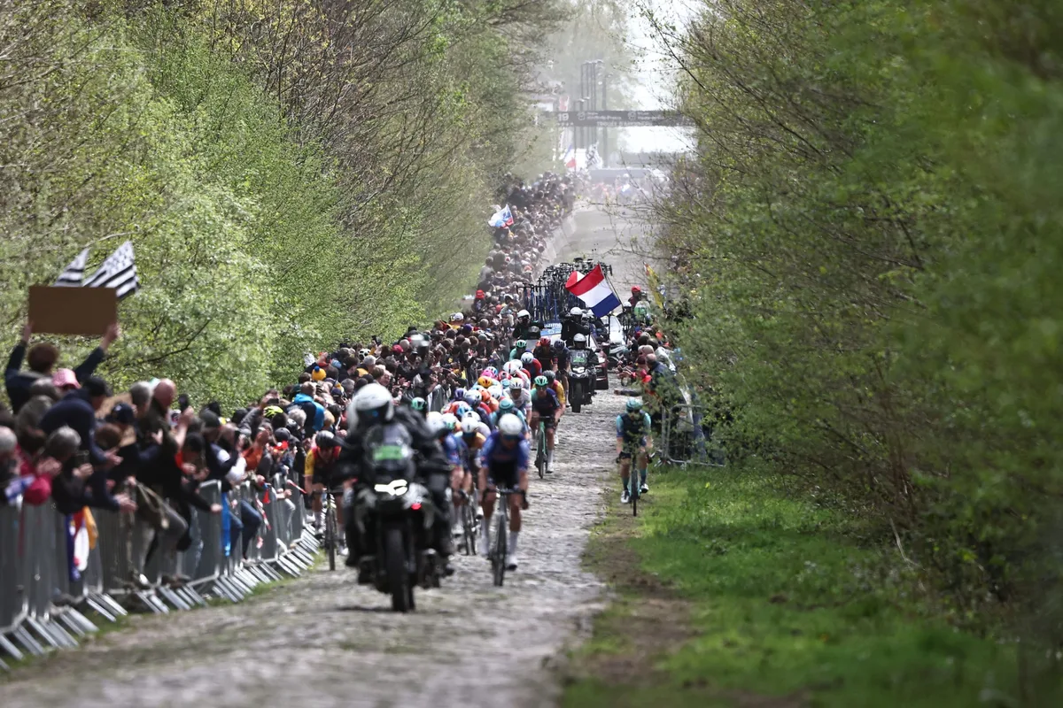 The leading pack rides on the 'Trouée d'Arenberg' cobblestone sector (Arenberg trench) during the 123rd edition of the Paris-Roubaix one-day classic cycling race, 258.3 km between Compiègne and Roubaix, northern France, on April 12, 2026. (Photo by Anne-Christine POUJOULAT / AFP via Getty Images)