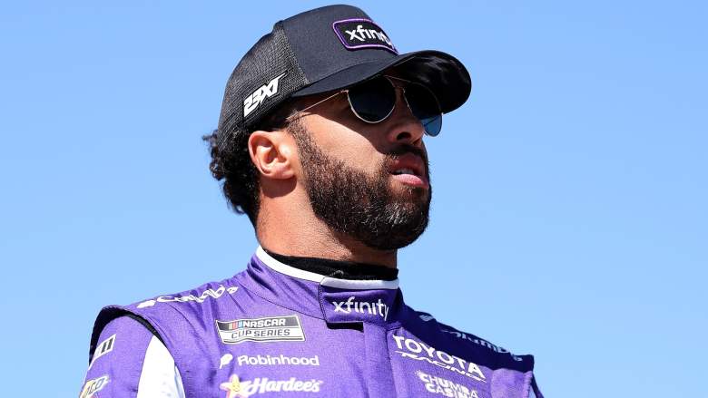 Bubba Wallace wearing a purple firesuit and sunglasses during NASCAR Cup Series practice at Kansas Speedway