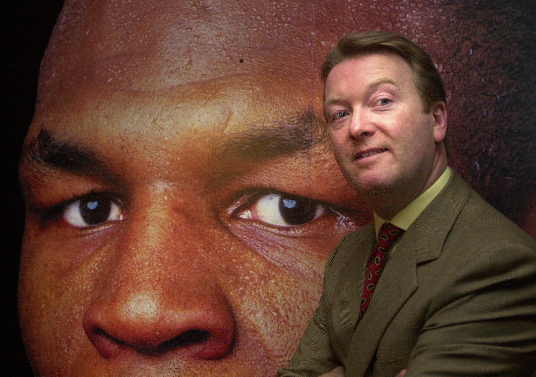 Frank Warren stands in front of a large poster of Mike Tyson in 2000
