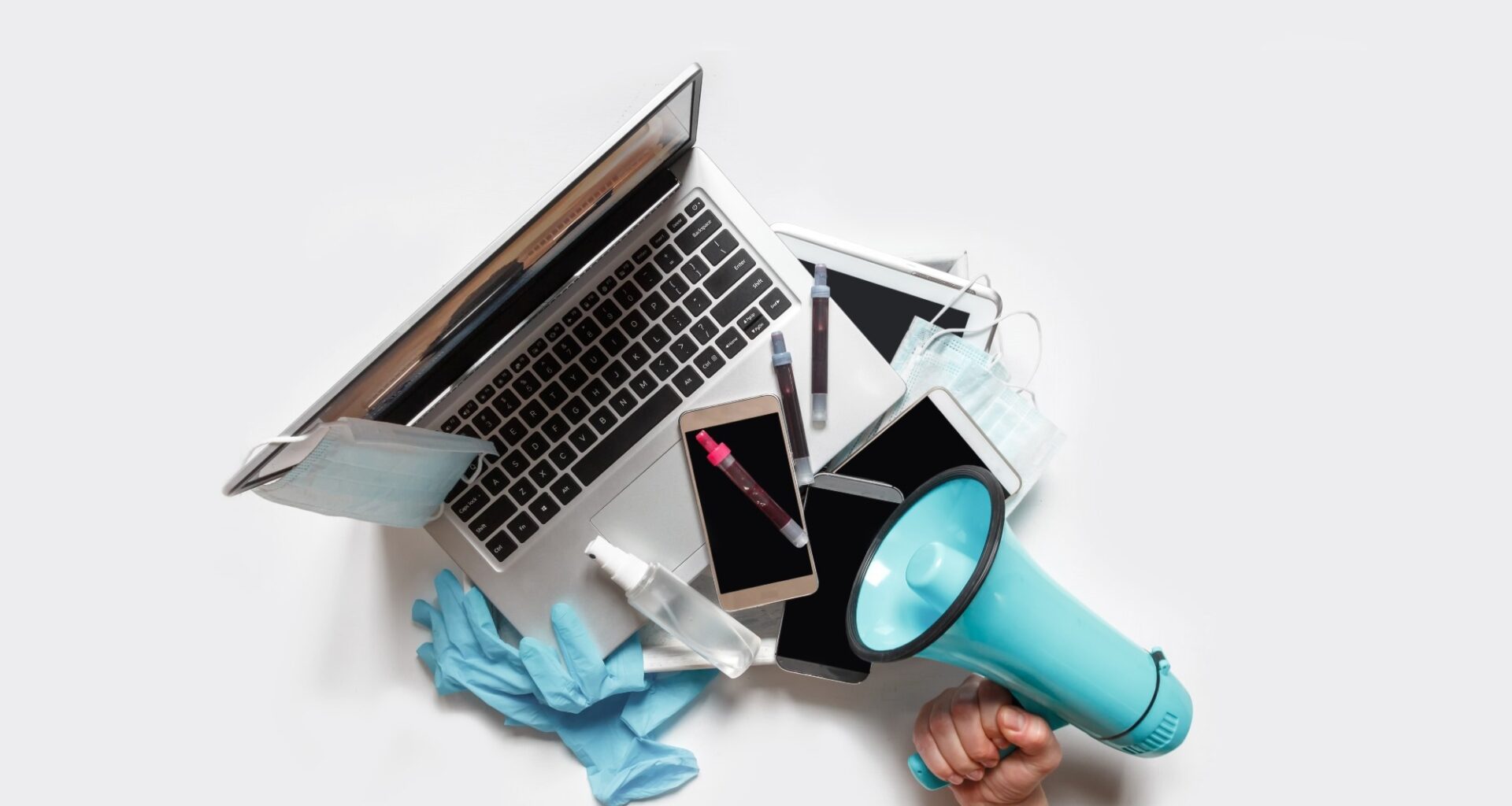 Hands holding a tray with digital gadgets. Laptop. Phone from which they broadcast information. Hand with megaphone to the right