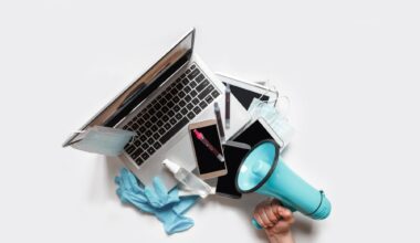 Hands holding a tray with digital gadgets. Laptop. Phone from which they broadcast information. Hand with megaphone to the right
