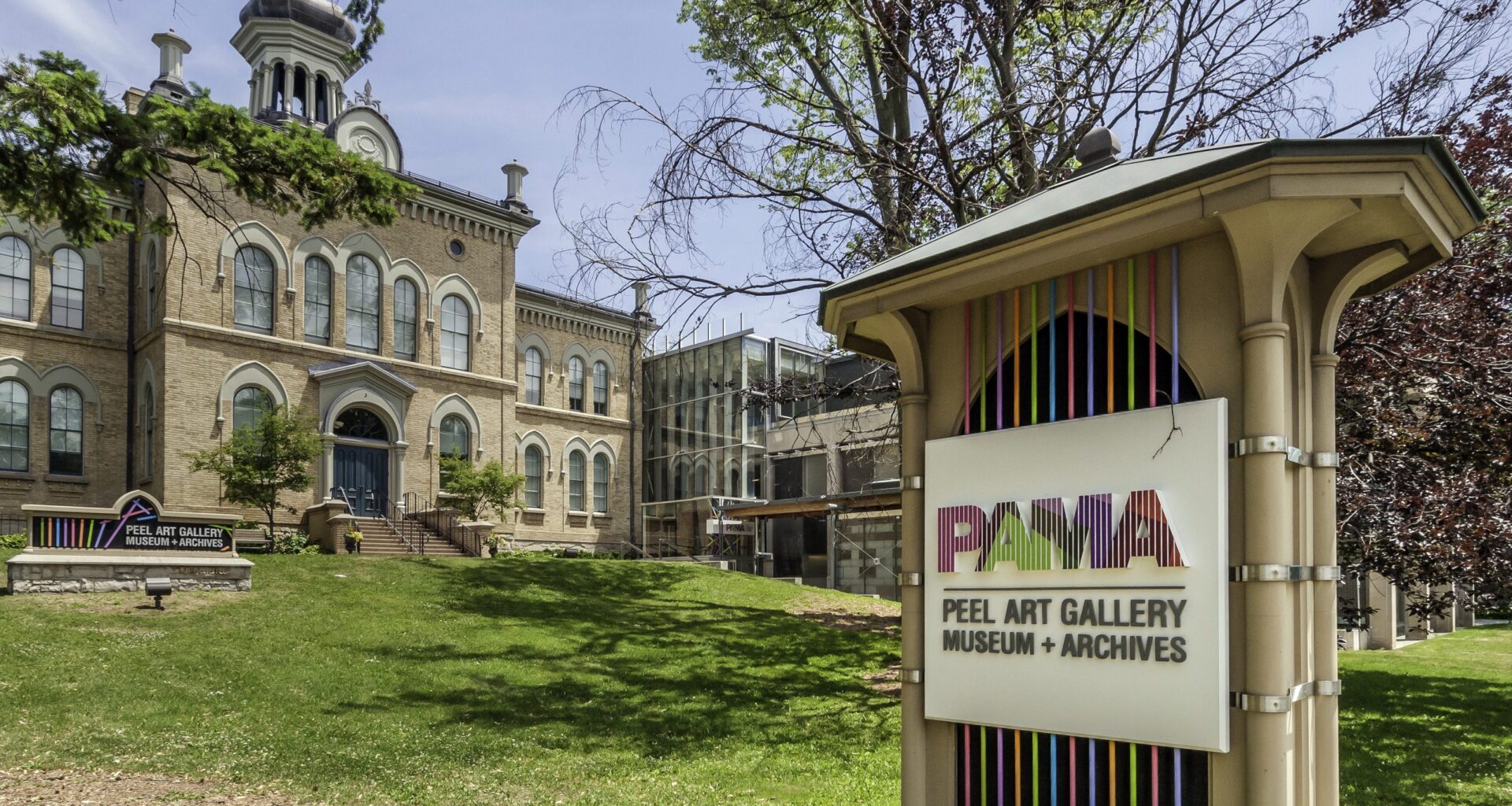 A outdoor image of a historical building, landscpaing and a sign out front