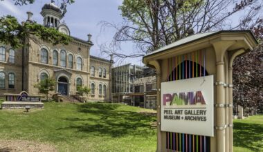 A outdoor image of a historical building, landscpaing and a sign out front