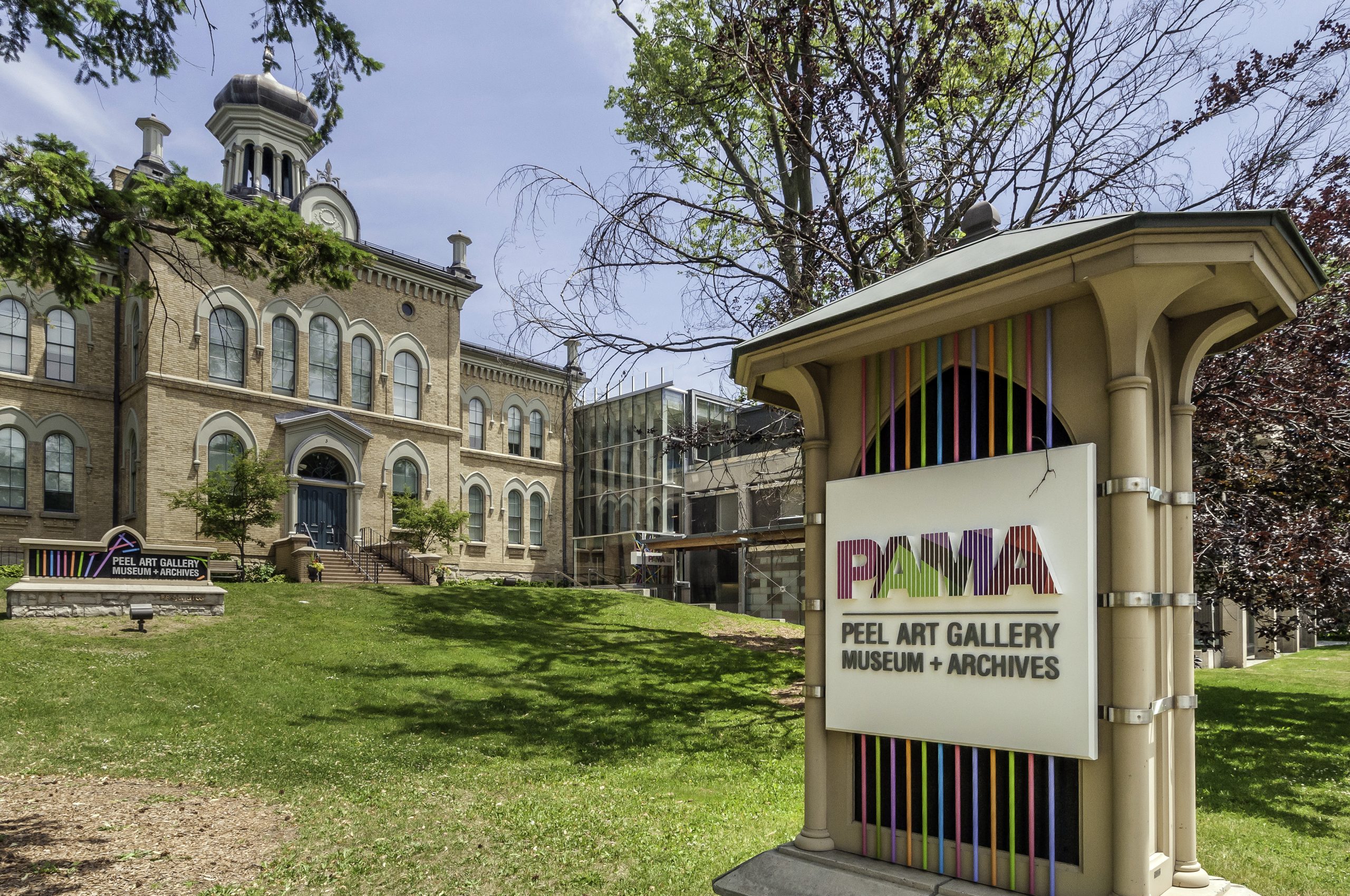 A outdoor image of a historical building, landscpaing and a sign out front