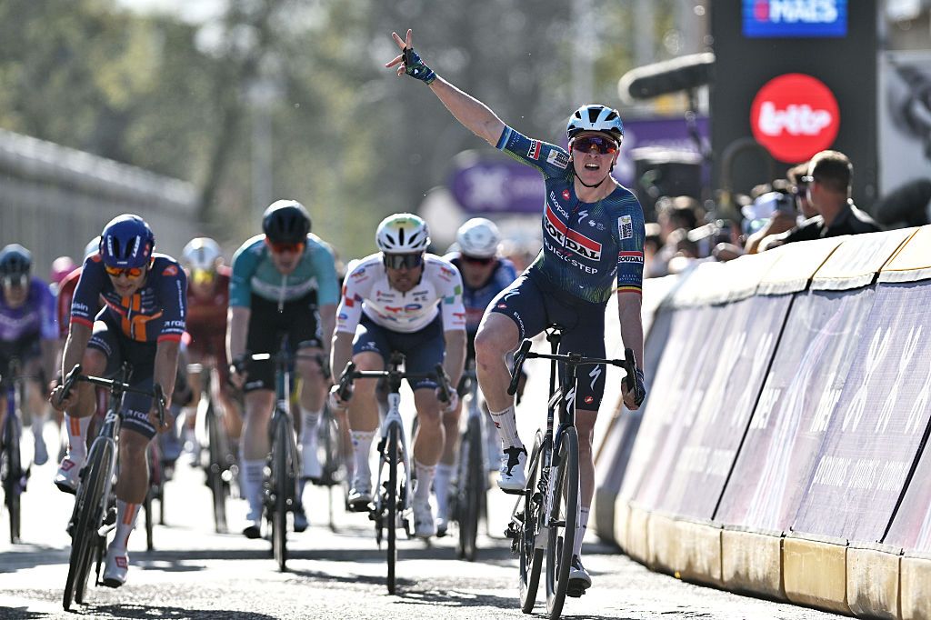 Tim Merlier celebrates his win with one arm raised