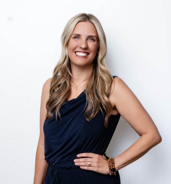 5 Things I Wish I Knew About Money in My 30s - 2 Woman with long blonde hair wearing a navy sleeveless dress, standing against a plain white background and smiling at the camera, ready to share financial tips for managing money in my 30s.