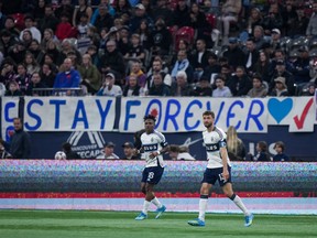 Whitecaps players on the field in front of a sign that says