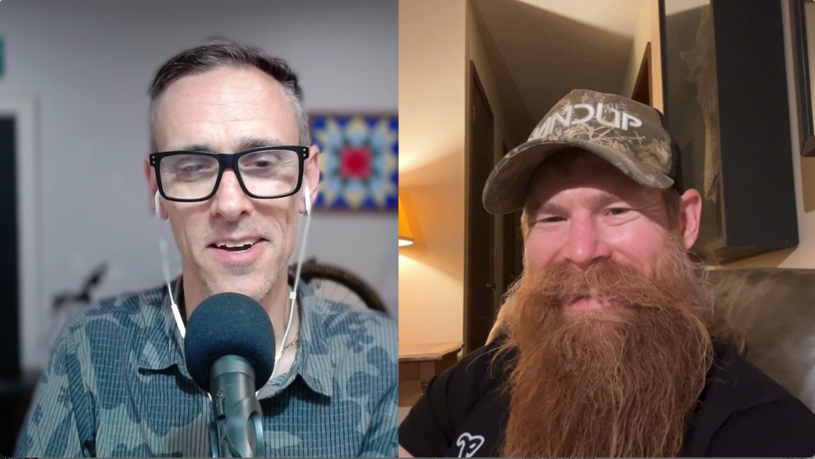 A split-screen image featuring two men smiling at the camera. The man on the left has short, gray hair, wears glasses, and a patterned shirt, speaking into a microphone with earphones. The man on the right has a long red beard, wears a camouflage baseball cap, and is seated in a well-lit indoor space with a cozy ambiance.