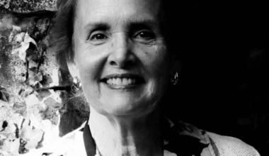 Black and white headshot of a woman with short hair wearing a floral blouse.