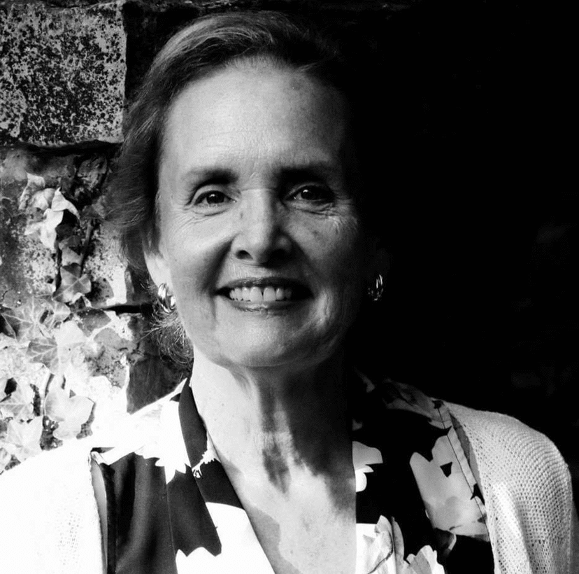 Black and white headshot of a woman with short hair wearing a floral blouse.