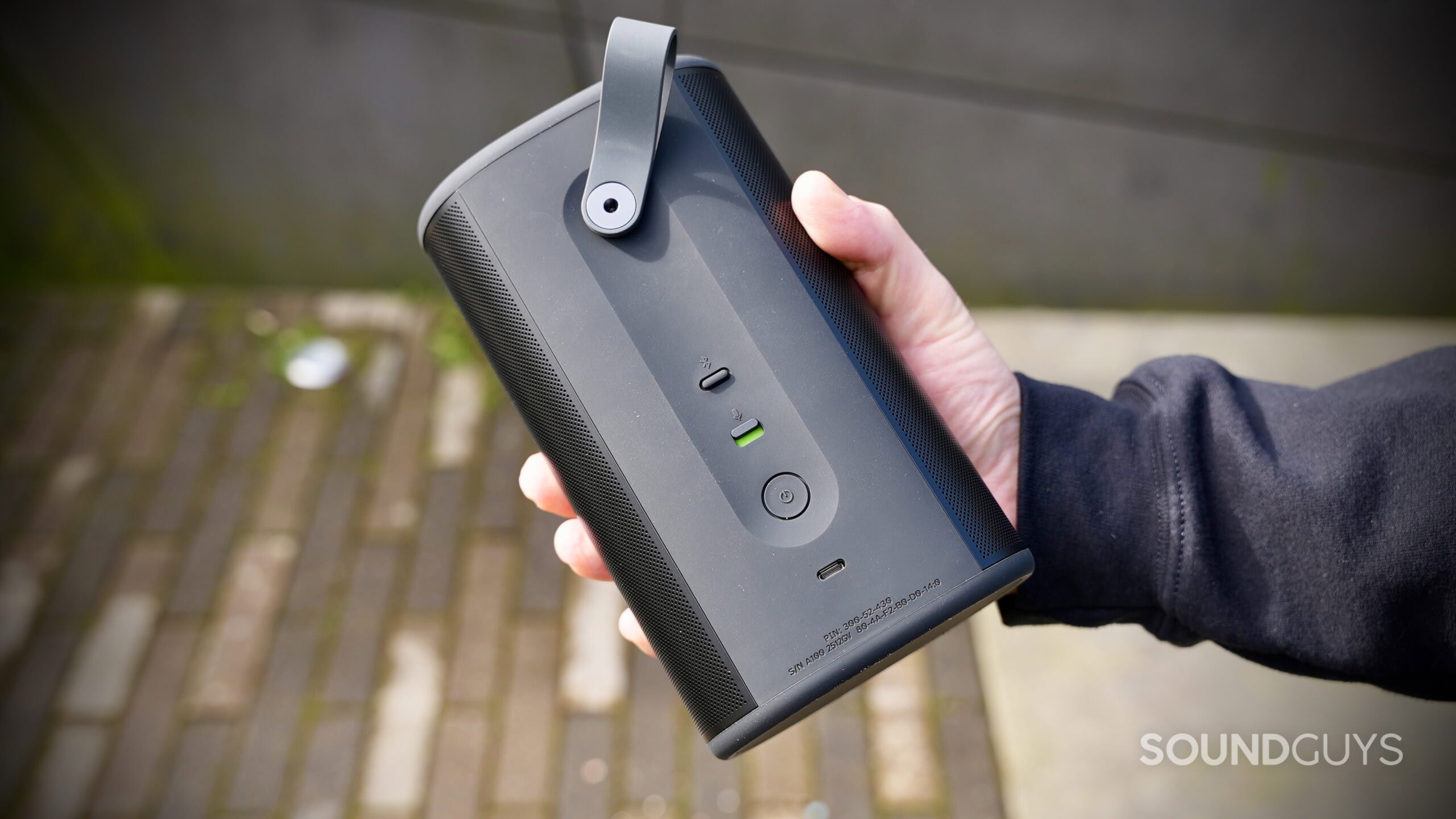 A hand holding the Sonos Play portable speaker showing the rear controls and ports.