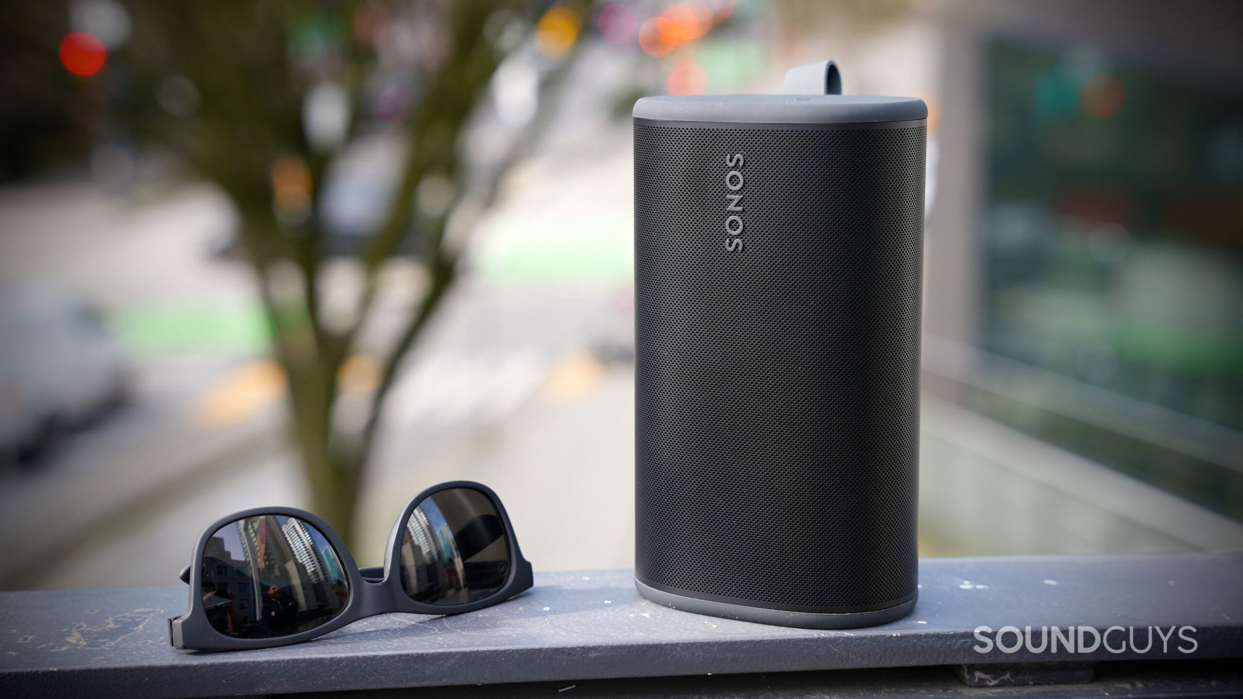 The Sonos Play portable speaker standing upright on a ledge next to a pair of sunglasses.