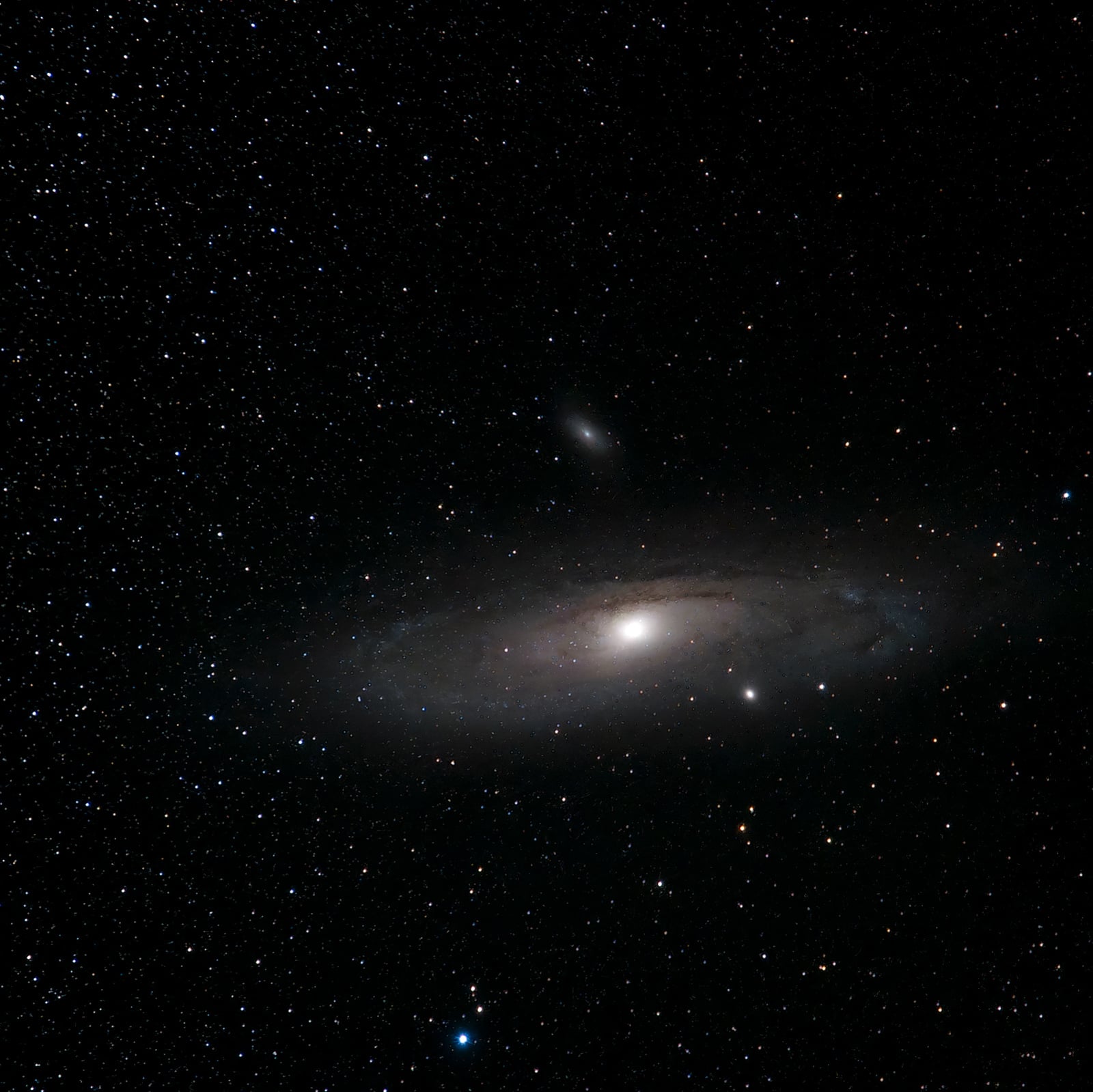 The image shows a spiral galaxy, likely the Andromeda Galaxy, surrounded by countless stars against the dark backdrop of space. The galaxy's bright center and spiral arms are visible.