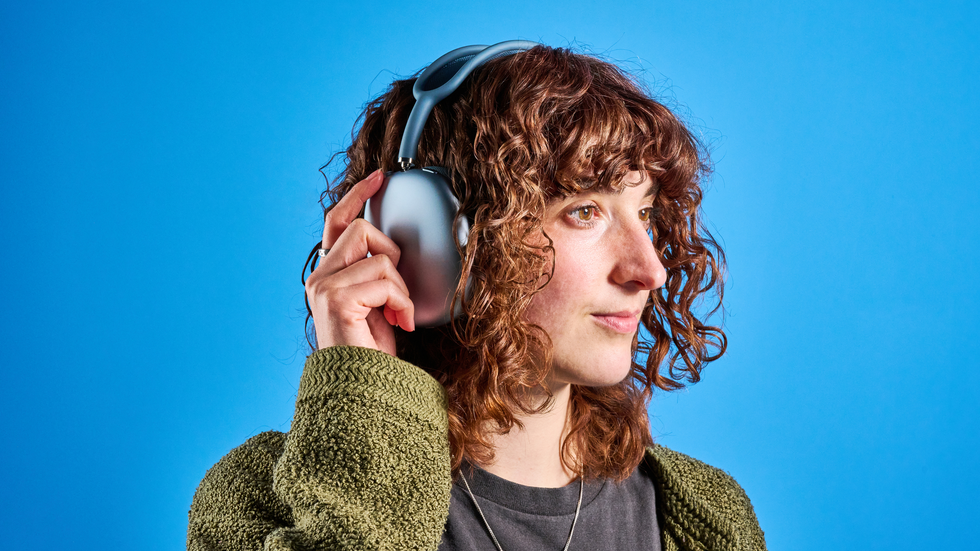 the apple airpods max 2 in blue photographed against a blue tom's guide background, showing the mesh headband, anodized aluminum ear cups, carry case, and controls