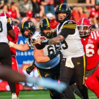 Jun 7, 2025; Calgary, Alberta, Canada; Hamilton Tiger-Cats quarterback Bo Levi Mitchell (19) looks to pass against the Calgary Stampeders with Jaylon Hutchings (96) chasing him down during the second half at McMahon Stadium.