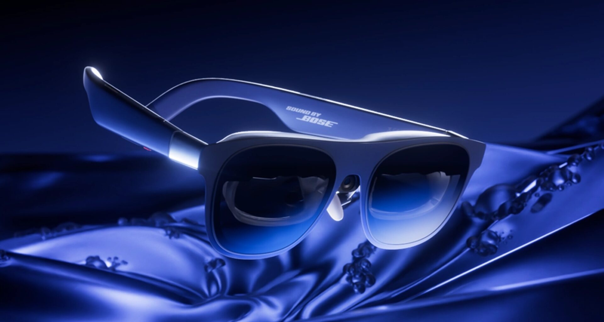 Blue Bose sunglasses resting on silky blue fabric, logo visible on the arm.