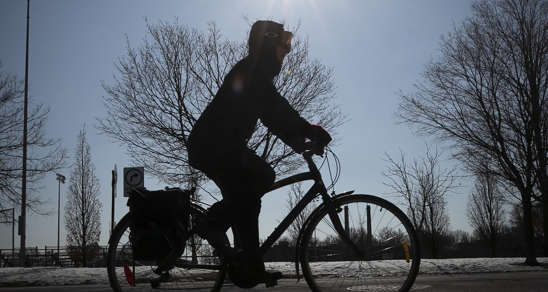 A cyclist rides with the sun in the background.