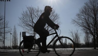 A cyclist rides with the sun in the background.