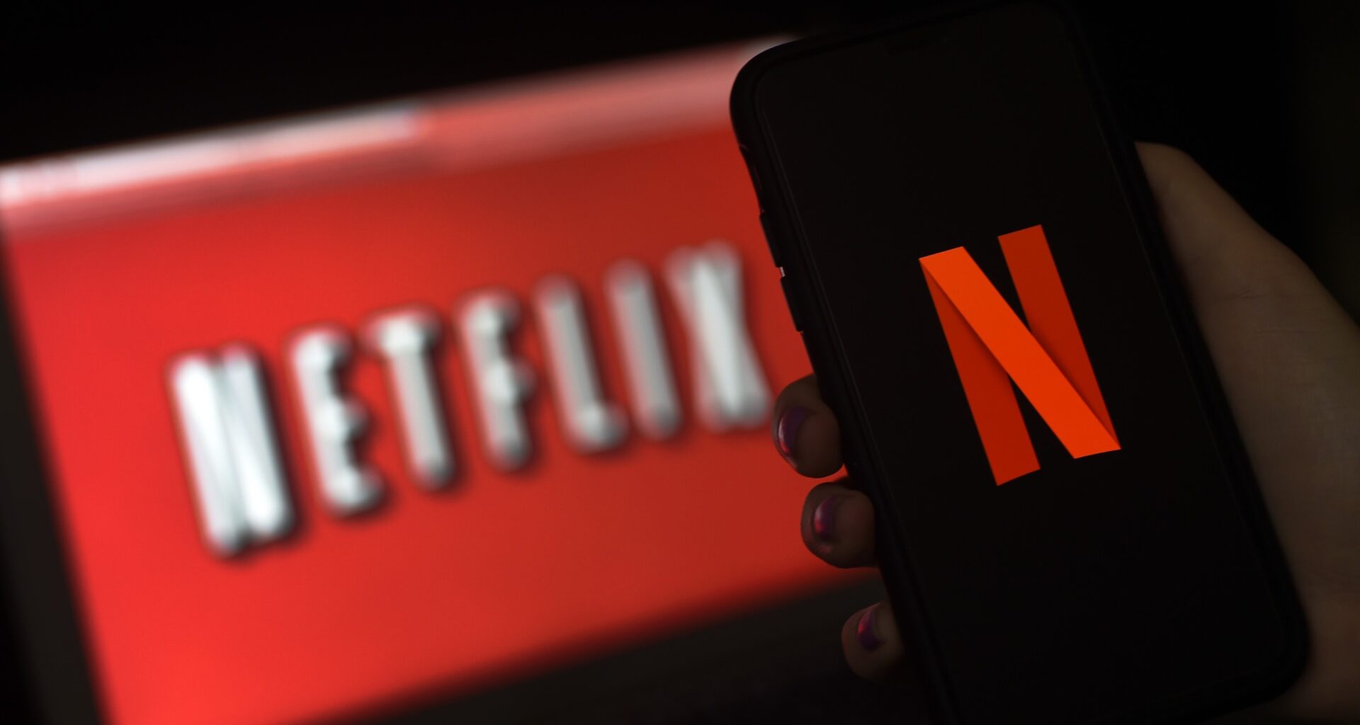 a computer screen and mobile phone display the Netflix logo.
