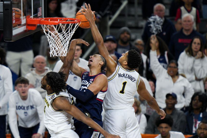 Michigan guard Trey McKenney blocks the shot of UConn's Jayden Ross in the second half of Monday's title game.