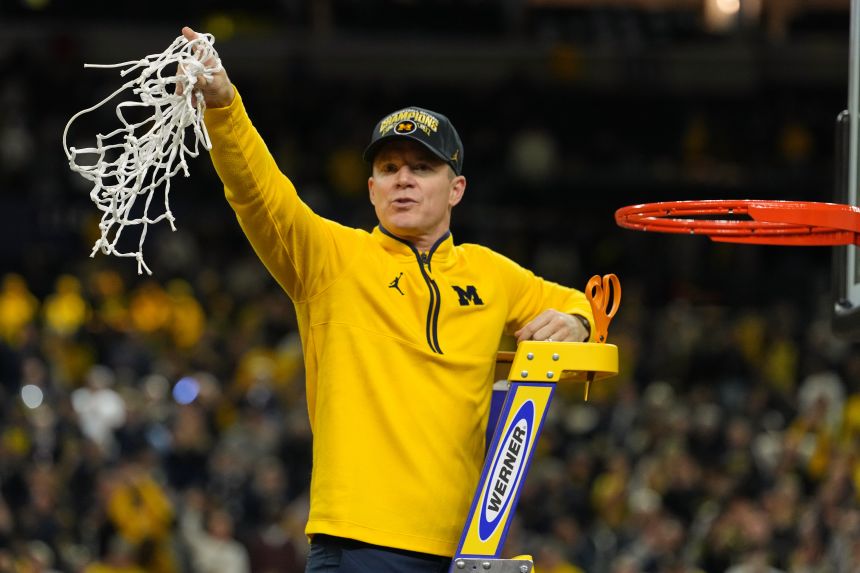 Michigan head coach Dusty May celebrates Monday's win by cutting down the net.