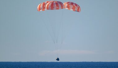 Integrity, dangling from three red and white parachutes, about to splash down in the Pacific Ocean.