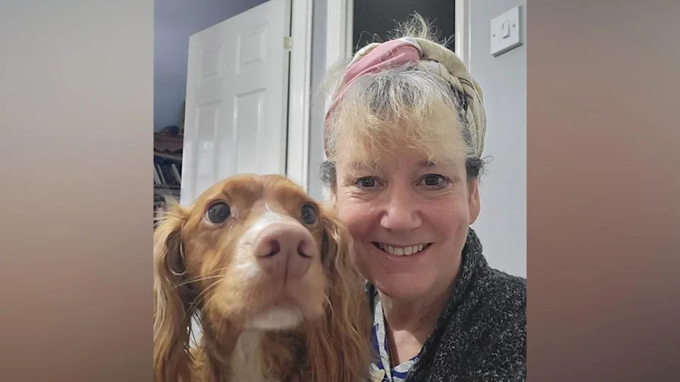 A picture of Katie Banfield and her dog, Alfie. Katie is smiling and has blonde hair and Alfie is a brown spaniel. The picture is a selfie and Alfie looks slightly off to the side while Katie looks directly at the camera. She is wearing a black, patterned jumper.