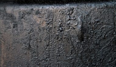 A textured black surface with a few faint scratches and markings.