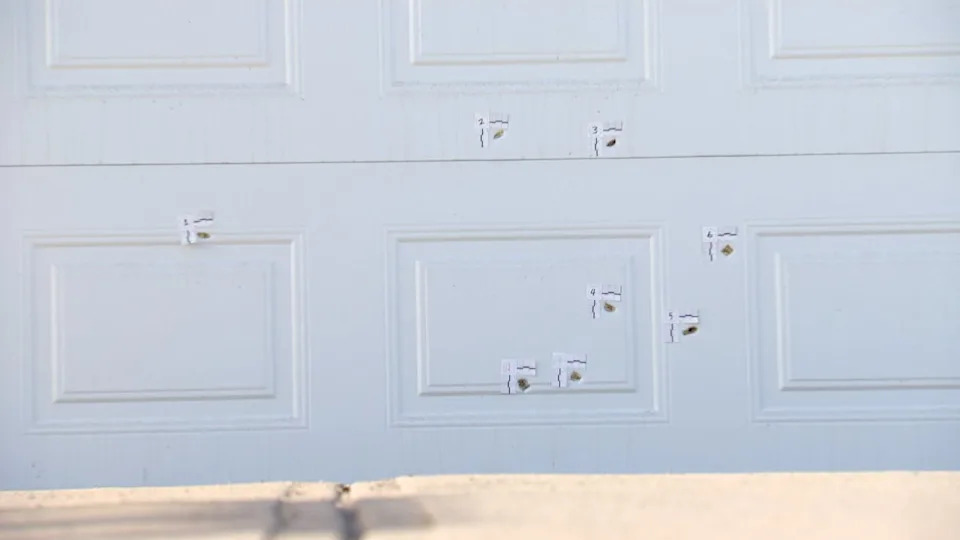 Bullet holes pierce the  garage door of a home in the community of Saddle Ridge, in what police say was an extortion-related shooting.