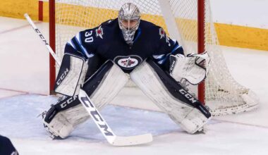 Connor Hellebuyck, star goaltender for the Winnipeg Jets, in focused butterfly stance in full navy blue and white gear in front of the net during an NHL game, amidst recent trade rumors.