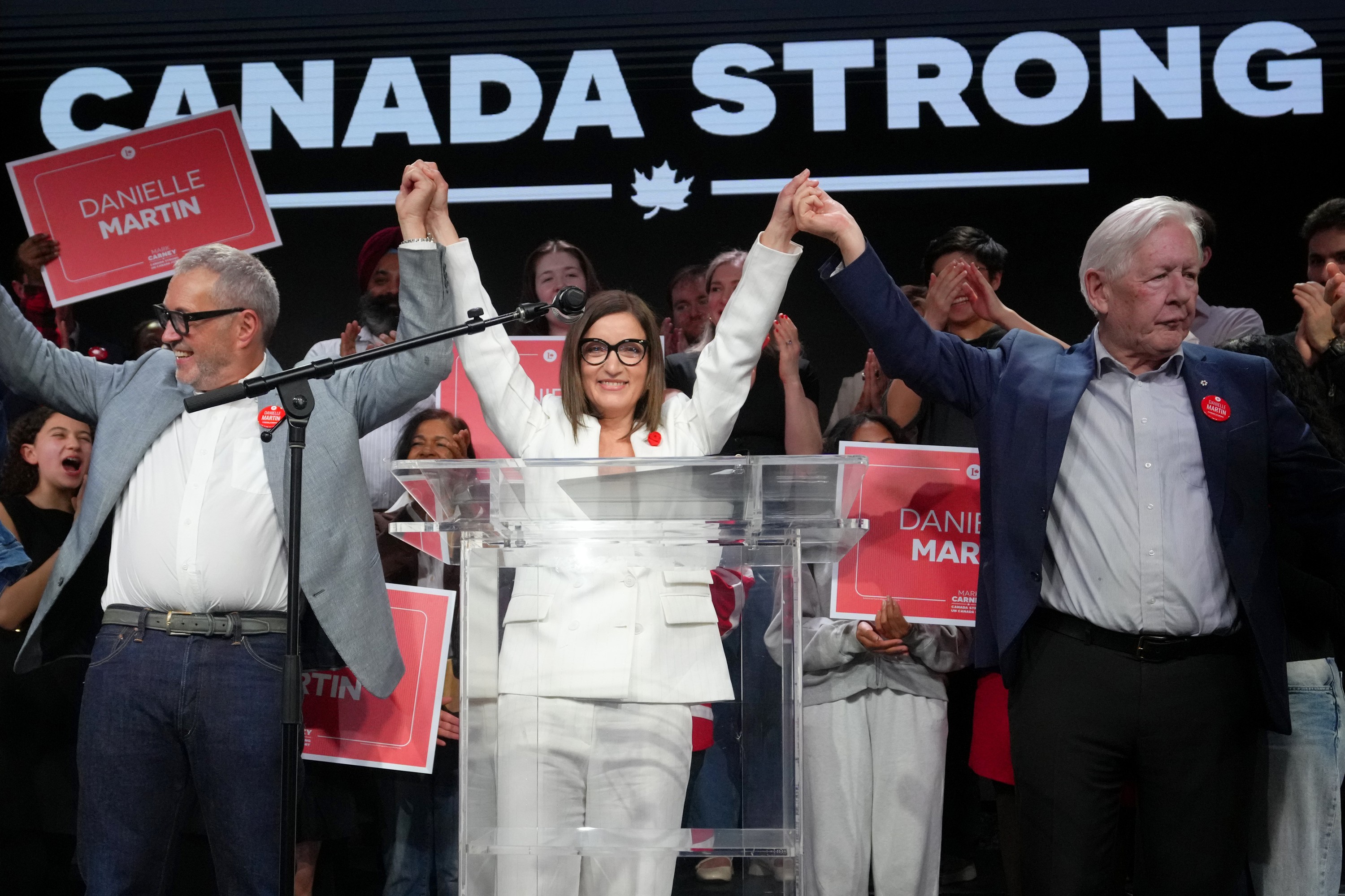 Danielle Martin stands on stage with supporters under a banner reading Canada Strong.